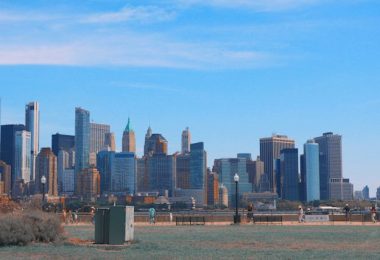A view of Jersey City’s skyline from the waterfront, showing tall buildings against a blue sky